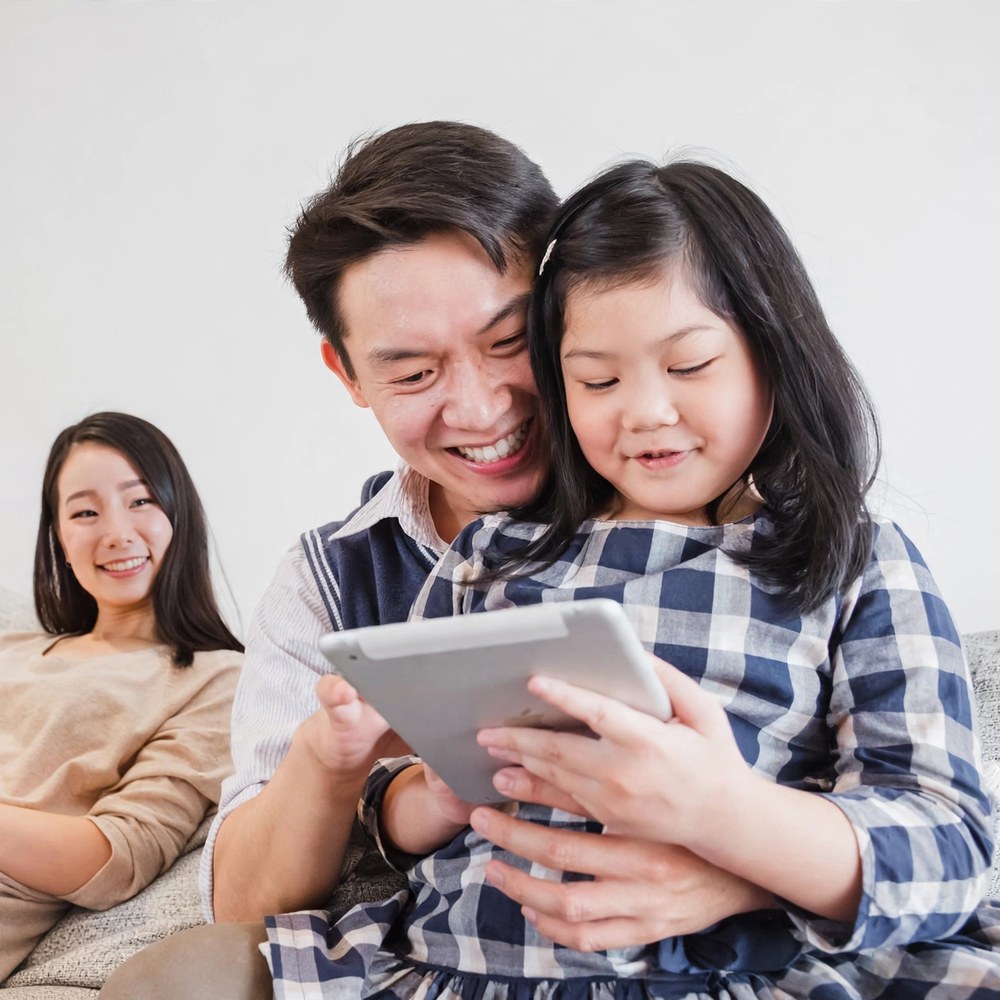 Happy family learning English together on a tablet and laptop